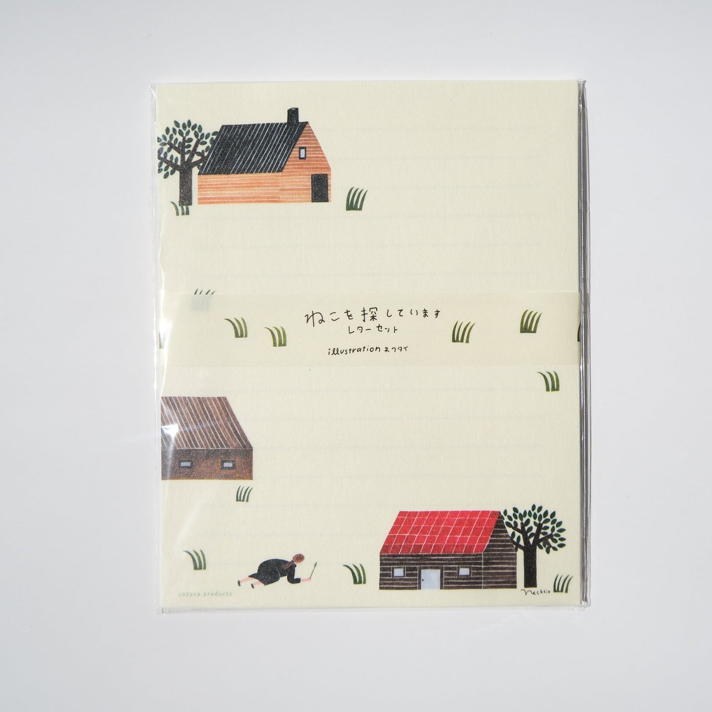 A vertical notepad with a cream-colored cover featuring minimalist illustrations of small houses, trees, and grass, photographed against a plain white background.