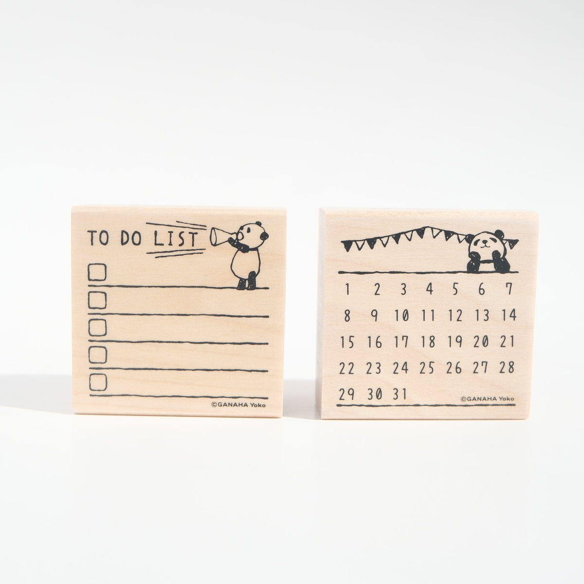 Two small wooden desk accessories with black printed illustrations: a to-do list pad on the left and a daily calendar pad on the right, both on a clean white background.