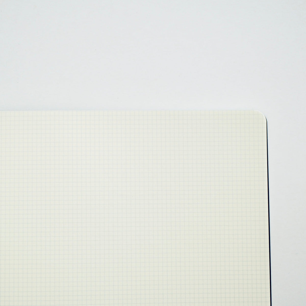 An open notebook with blank, off-white grid paper pages on a clean white background.