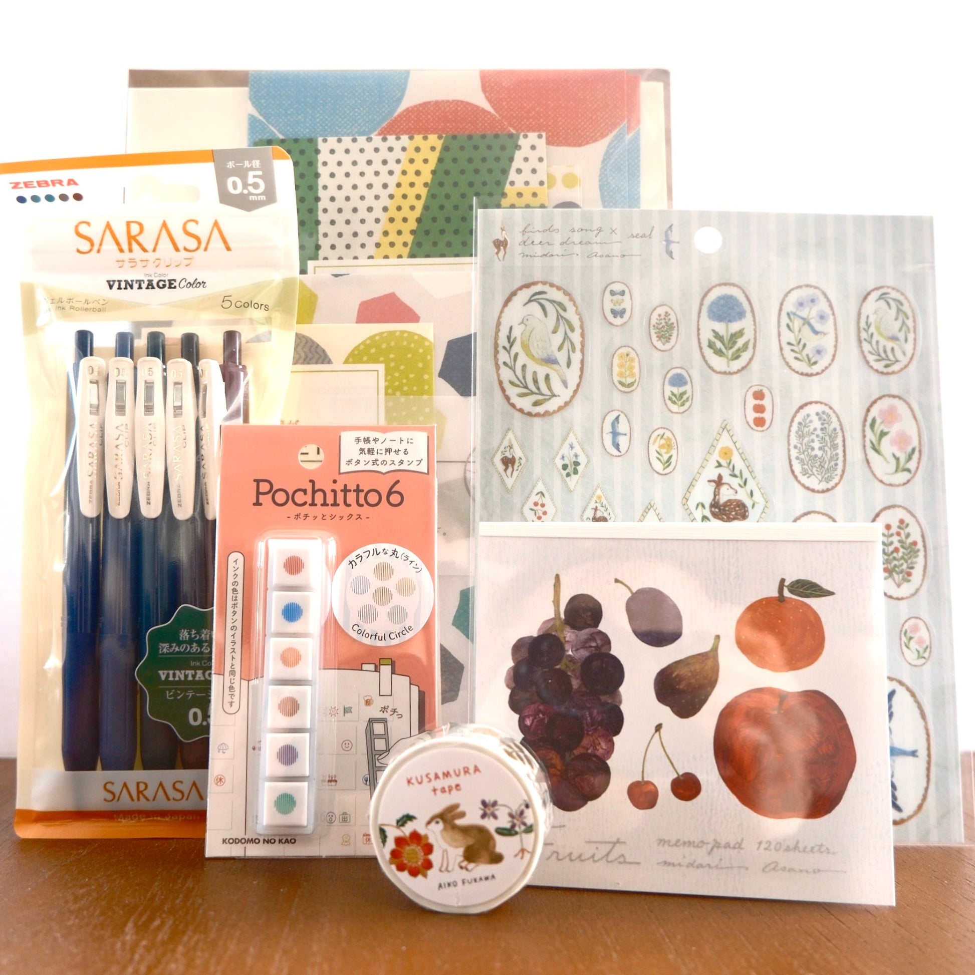 Collection of stationery items including pens, stickers, and a small round item on a wooden surface.