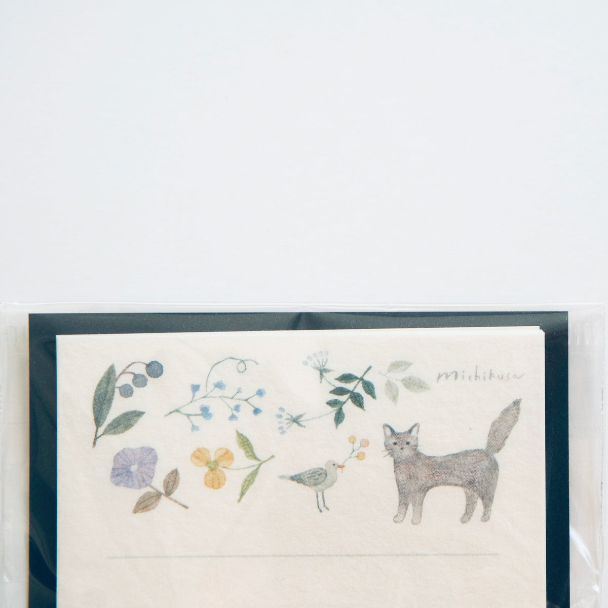 A framed art print featuring a watercolor illustration of a gray fox, blue berries, green leaves, and a small bird on an off-white background, enclosed in a clear protective sleeve against a plain white wall.