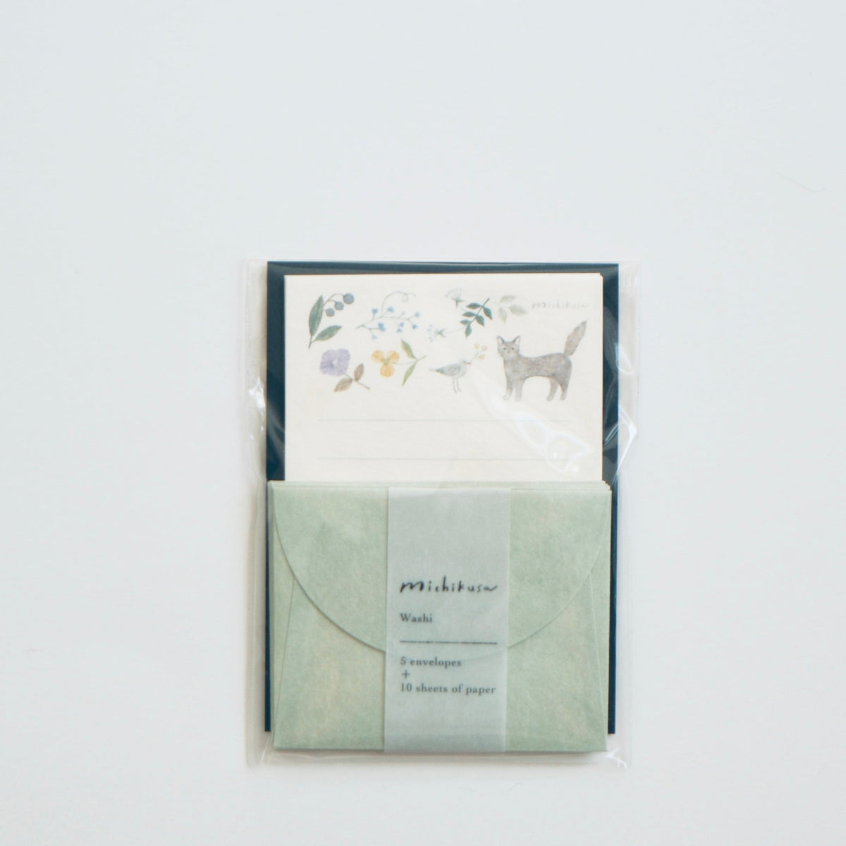 A stationery set in clear plastic wrapping, featuring a sage green envelope with a white paper band and a matching floral card, displayed against a clean white background.