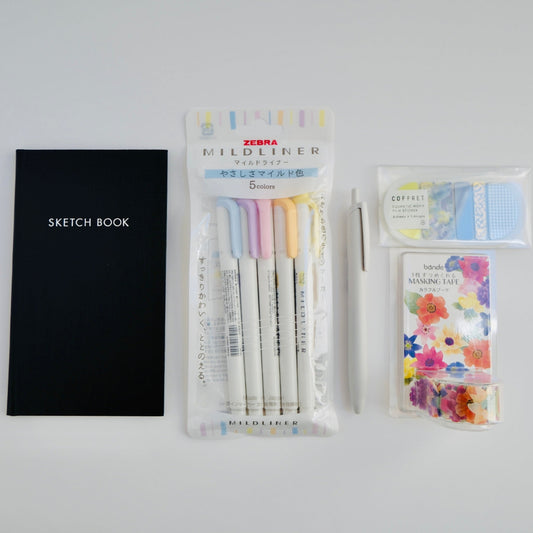 Paper Bento beta box with five Japanese stationery items including Uni Jetstream pen, Zebra Mildliners, KOKUYO notebook, Bande washi tape, and King Jim stickers arranged flat lay
