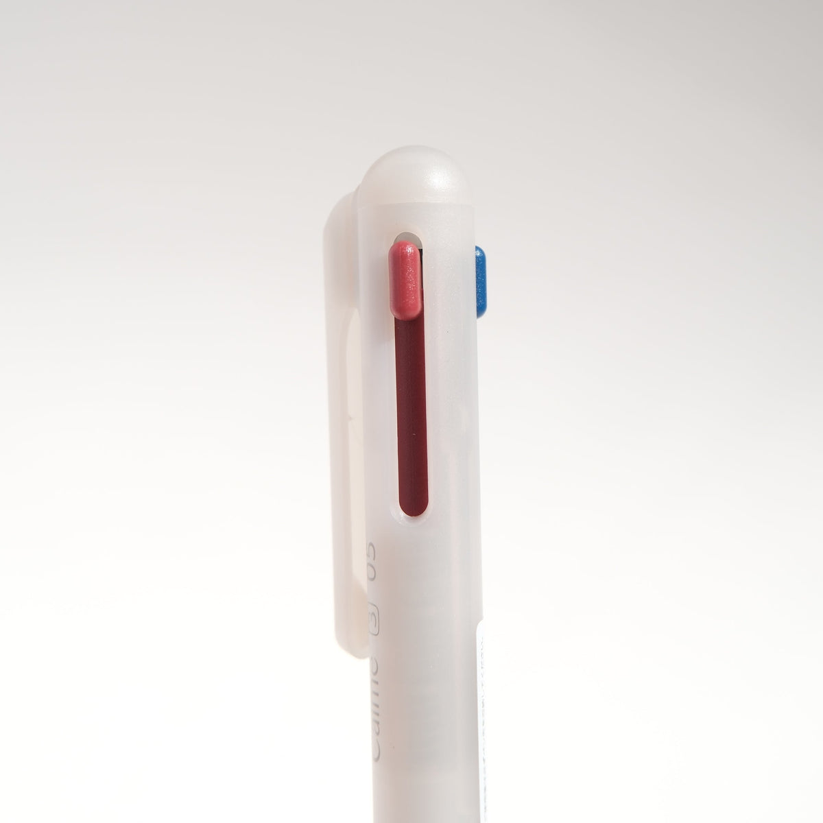 A close-up side view of a retractable pen with a translucent white plastic body, featuring a red ink cartridge visible through a vertical window and a small blue button on the side, set against a plain white background.